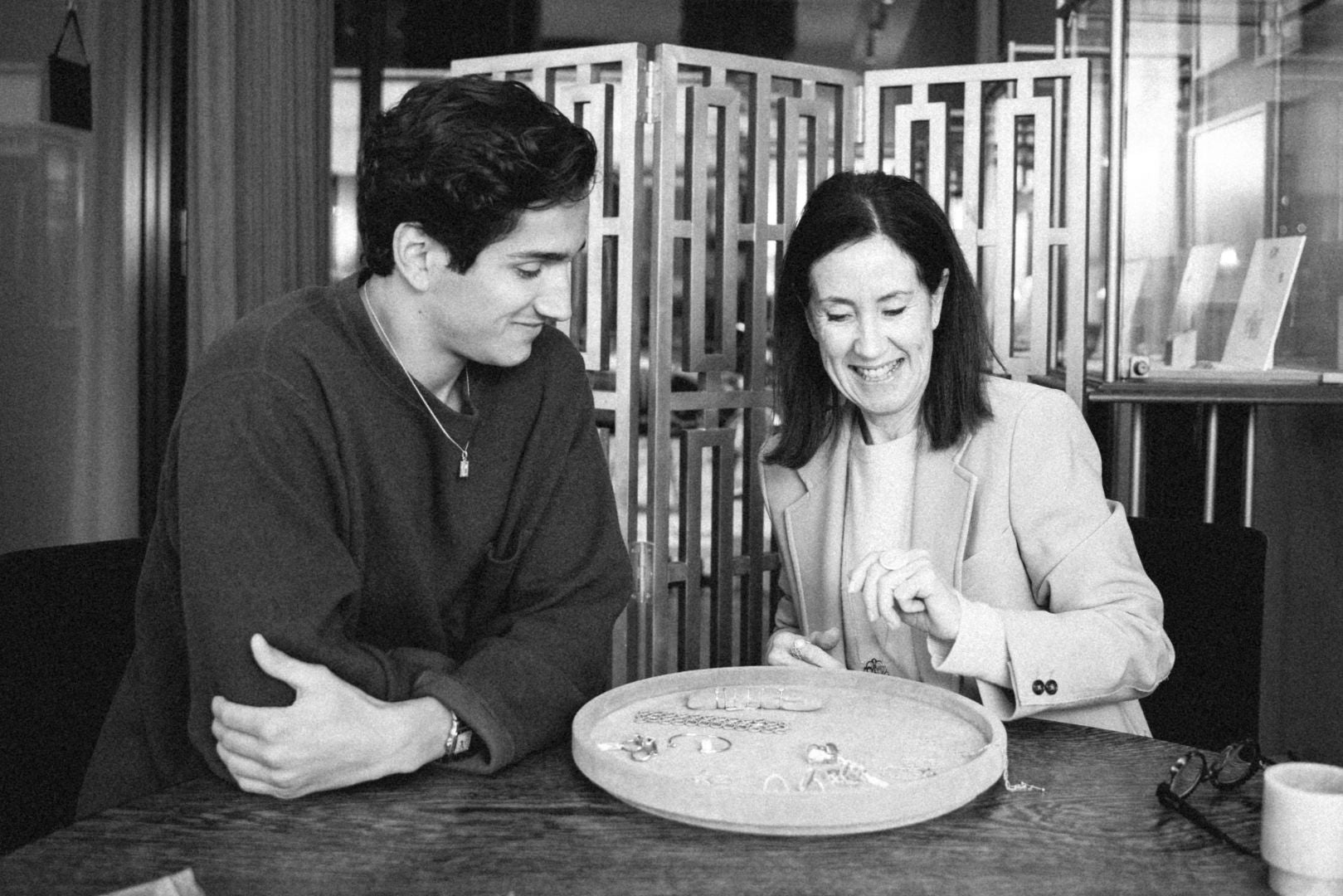 mother and son smiling sitting at a table inside of O! Jewelry 