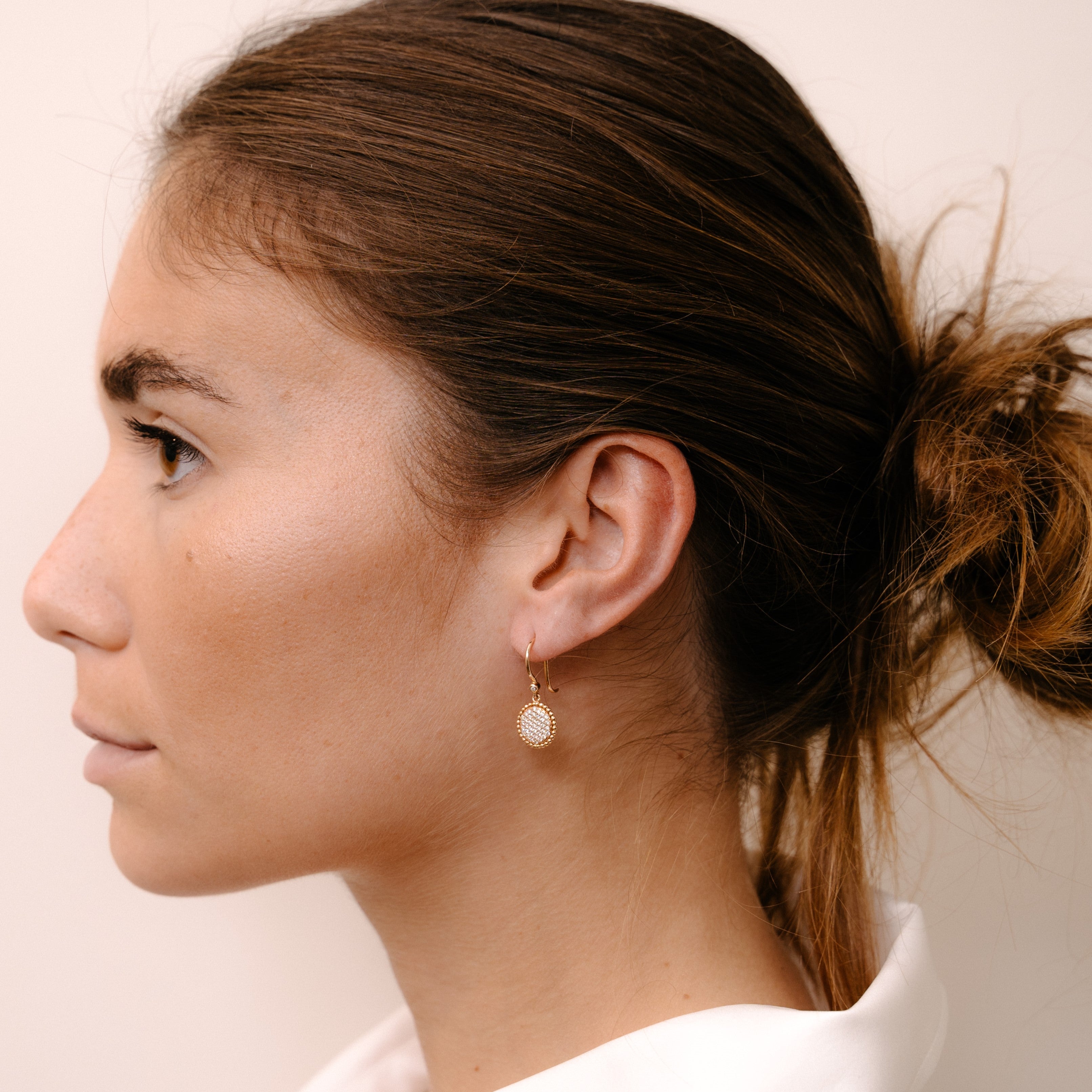 Model wearing circular earring with diamond plateau by O! Jewelry on one side