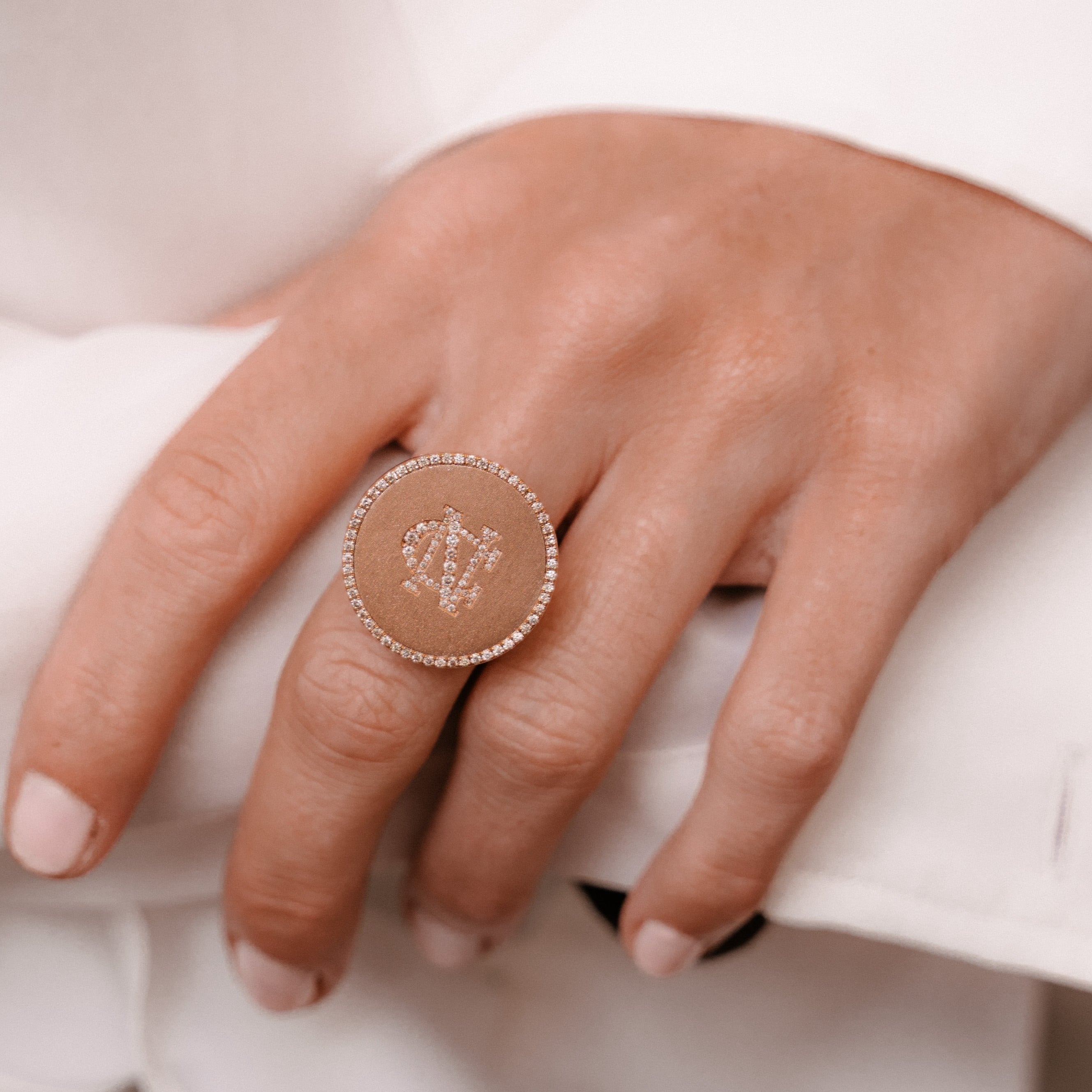 Circular rose ring on hands with initials set in diamonds made by O! Jewelry