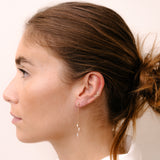 Model wearing diamond earring hanging on chain by O! Jewelry on one side