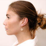 Model wearing circular earring with partial diamonds by O! Jewelry on one side